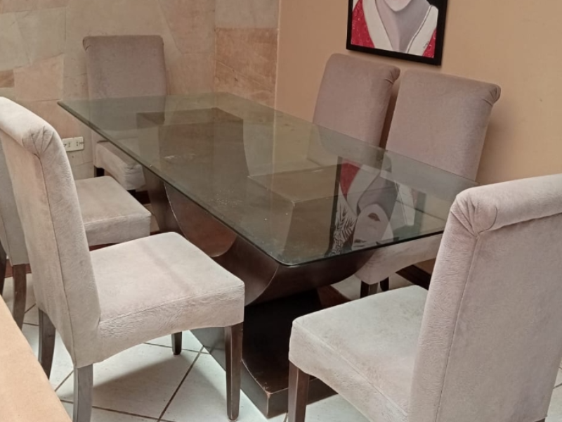 Mesa de vidrio con base de finos acabados y sillas tapizadas